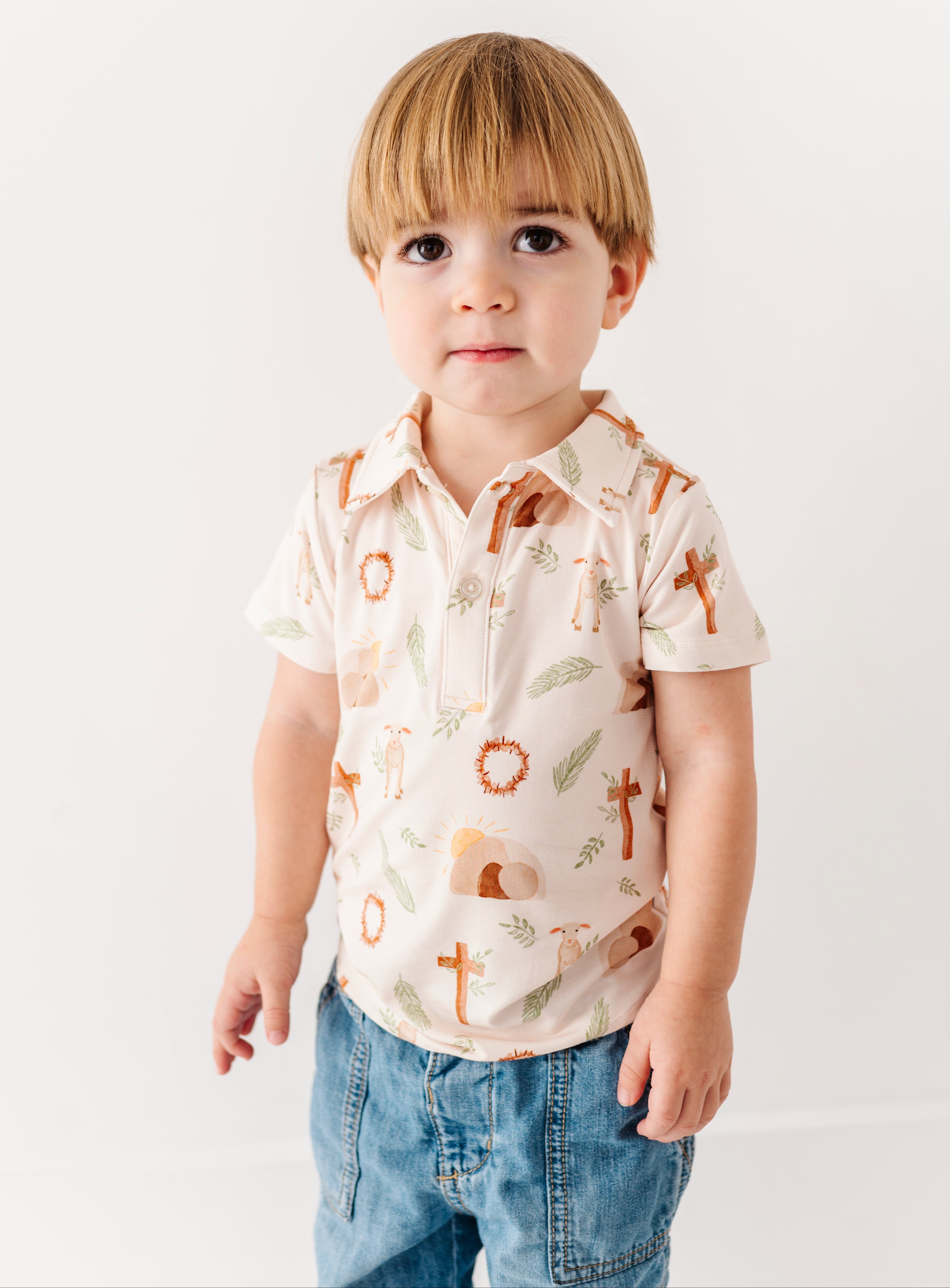 Little boy wearing an Easter themed bamboo polo shirt on a plain background